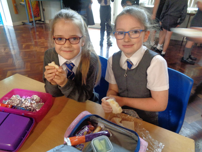Two girls enjoying their packed lunches