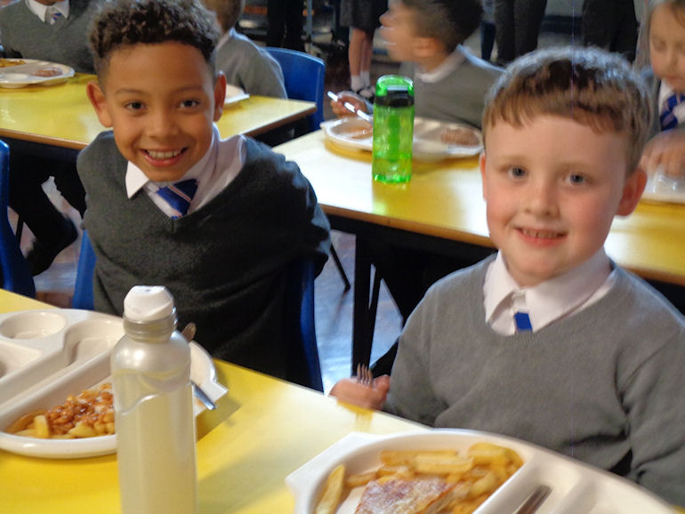 Two boys enjoying their school dinners