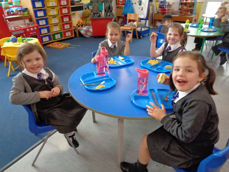 Children around a table eating their school dinners
