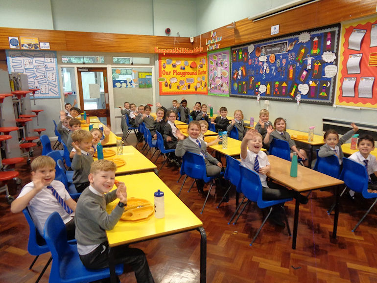 Children waving during school dinner time